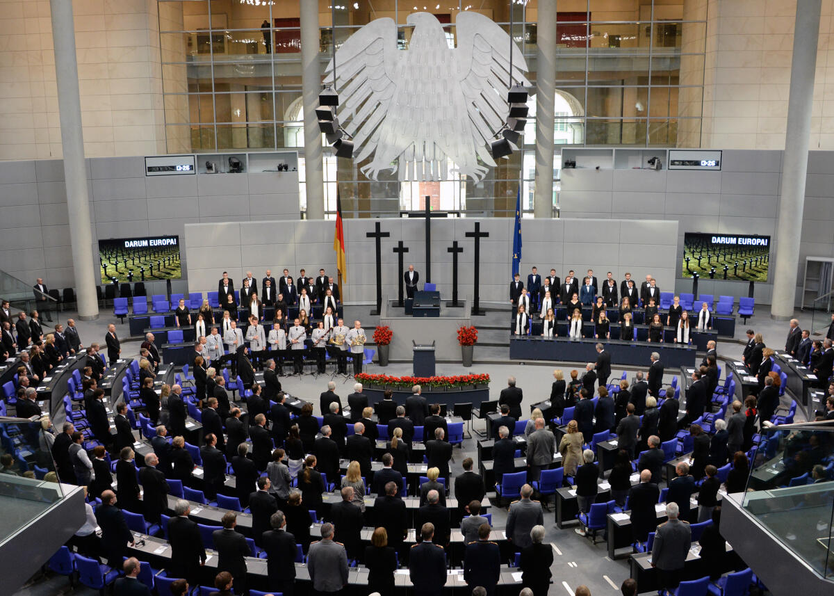 Zentrale Gedenkveranstaltung des Volksbundes Deutsche Kriegsgräberfürsorge e. V. am Volkstrauertag 2019 im Plenarsaal des Deutschen Bundestages im Reichstagsgebäude. Die Begrüßungsrede hält der Präsident des Volksbundes, Wolfgang Schneiderhan, die Gedenkrede hält der Stadtpräsident von Wroclaw (Breslau) a. D., Dr. Rafal Dutkiewicz, das Totengedenken spricht Bundespräsident Frank-Walter Steinmeier. Als Vertreter für den Bundestag nimmt Bundestagsvizepräsident Wolfgang Kubicki teil. Die Veranstaltung wird musikalisch vom Bundeswehr-Musikkorps und dem Landesjugendchor und Kammerchor (beide hier im Bild) begleitet.; Übersicht, Adler, Bundesadler, Kreuz, Kreuze, Blumen. Zentrale Gedenkveranstaltung des Volksbundes Deutsche Kriegsgräberfürsorge e. V. am Volkstrauertag 2019 im Plenarsaal des Deutschen Bundestages im Reichstagsgebäude. Die Begrüßungsrede hält der Präsident des Volksbundes, Wolfgang Schneiderhan, die Gedenkrede hält der Stadtpräsident von Wroclaw (Breslau) a. D., Dr. Rafal Dutkiewicz, das Totengedenken spricht Bundespräsident Frank-Walter Steinmeier. Als Vertreter für den Bundestag nimmt Bundestagsvizepräsident Wolfgang Kubicki teil. Die Veranstaltung wird musikalisch vom Bundeswehr-Musikkorps und dem Landesjugendchor und Kammerchor (beide hier im Bild) begleitet.; Übersicht, Adler, Bundesadler, Kreuz, Kreuze, Blumen.