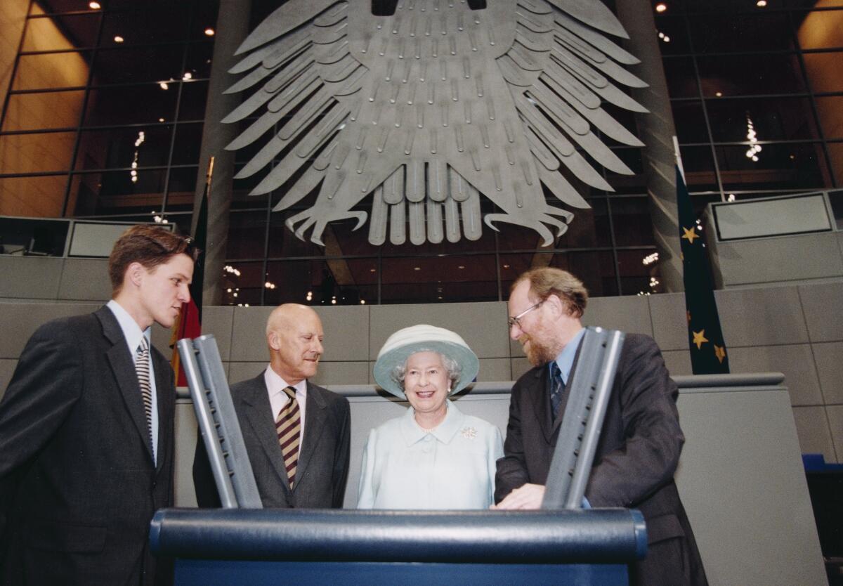 Thierse, Wolfgang; Queen, Elisabeth II.; Foster, Norman Bundestagspräsident Wolfgang Thierse, SPD, empfängt Queen Elisabeth II., Königin von England. Hier, v.l.: Sir Norman Foster (2. v. li.), Queen Elisabeth II. und Bundestagspräsident Wolfgang Thierse (re.), SPD, stehen hinter dem Rednerpult im Plenarsaal. Im Hintergrund der Bundestagsadler.