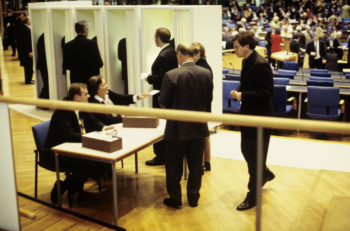 Die Konstituierende Sitzung der 14. Wahlperiode findet im neuen Bonner Plenarsaal statt.; Die Abgeordneten werden in alphabetischer Reihenfolge von den Schriftführern aufgerufen, um sich nach Entgegennahme der Stimmkarte an den Ausgabetischen in die Wahlkabinen zu begeben.; Bundestagsabgeordnete, Abgeordnete, Wahl, wählen, Abstimmung, abstimmen, Stimmzettel, Wahlkabine, Wahlurne, geheim Die Konstituierende Sitzung der 14. Wahlperiode findet im neuen Bonner Plenarsaal statt.; Die Abgeordneten werden in alphabetischer Reihenfolge von den Schriftführern aufgerufen, um sich nach Entgegennahme der Stimmkarte an den Ausgabetischen in die Wahlkabinen zu begeben.; Bundestagsabgeordnete, Abgeordnete, Wahl, wählen, Abstimmung, abstimmen, Stimmzettel, Wahlkabine, Wahlurne, geheim