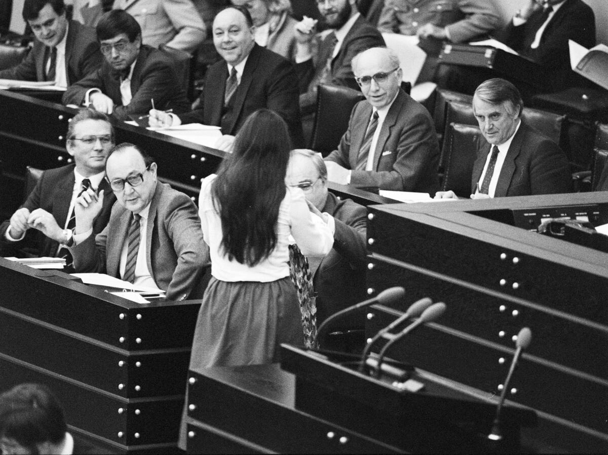 Christa Nickels, DIE GRÜNEN, MdB, überreicht Bundeskanzler Helmut Kohl (auf der Regierungsbank sitzend), CDU, nach ihrer Rede am 22.11.1983 eine Kette aus Papierkranichen, welche sie vorher um den Hals getragen hatte.; Bundestagsabgeordnete, Abgeordnete, Rednerpult Nickels, Christa; Kohl, Helmut; Genscher, Hans-Dietrich Christa Nickels, DIE GRÜNEN, MdB, überreicht Bundeskanzler Helmut Kohl (auf der Regierungsbank sitzend), CDU, nach ihrer Rede am 22.11.1983 eine Kette aus Papierkranichen, welche sie vorher um den Hals getragen hatte.; Bundestagsabgeordnete, Abgeordnete, Rednerpult