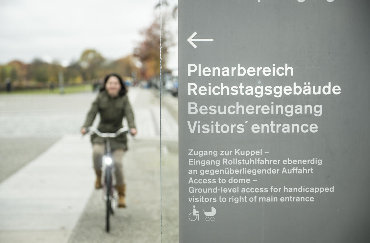 Baerbock, Annalena Annalena Baerbock, Bündnis 90/Die Grünen, MdB, fährt mit dem Fahrrad zur Arbeit in den Deutschen Bundestag. Im Vordergrund ist ein Wegweiser zum Reichstagsgebäude zu sehen.; Schild, Weg, Plenarbereich, Pfeil, Tafel, Wegweiser, Hinweisschild