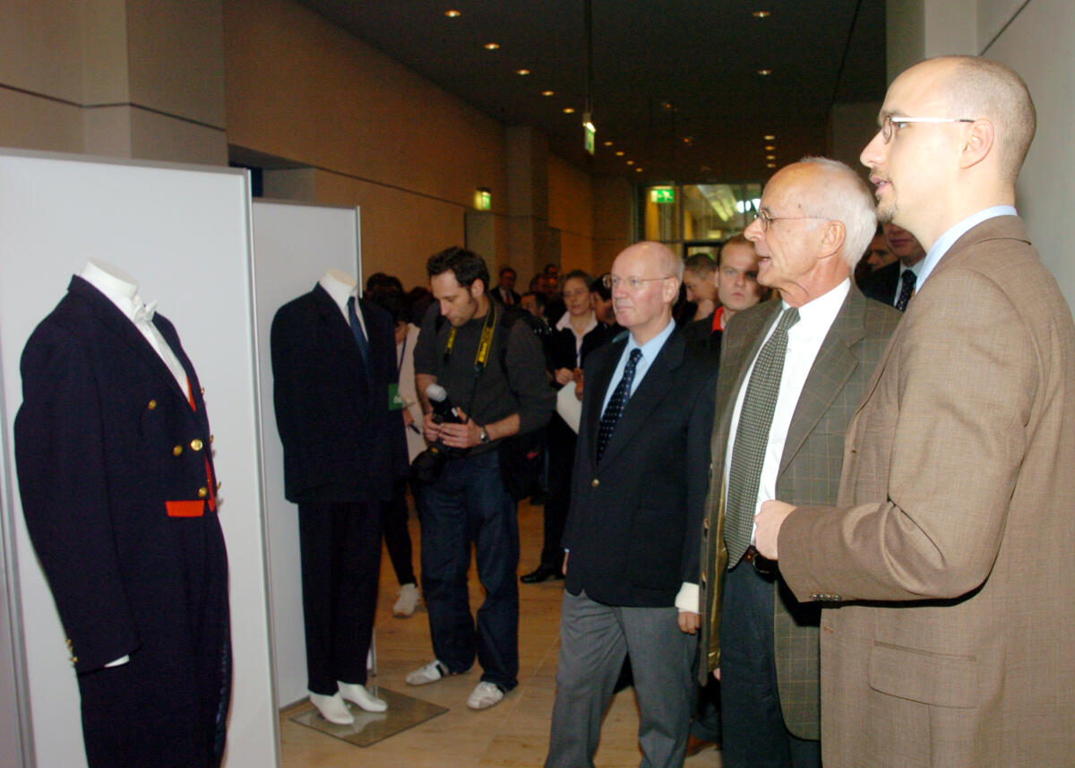 Zeh, Wolfgang; Kunze, Dirk; Stelzl, Hans-Joachim Prof. Dr. Wolfgang Zeh, Direktor beim Deutschen Bundestag, eröffnet die Ausstellung 50 Jahre Bundestagsfrack.; von links:  Dr. Hans-Joachim Stelzl, Abteilungsleiter Z, Prof. Dr. Wolfgang Zeh, Dirk Kunze, Plenarsekretär.; Frackmodelle, Bekleidung, Saaldiener