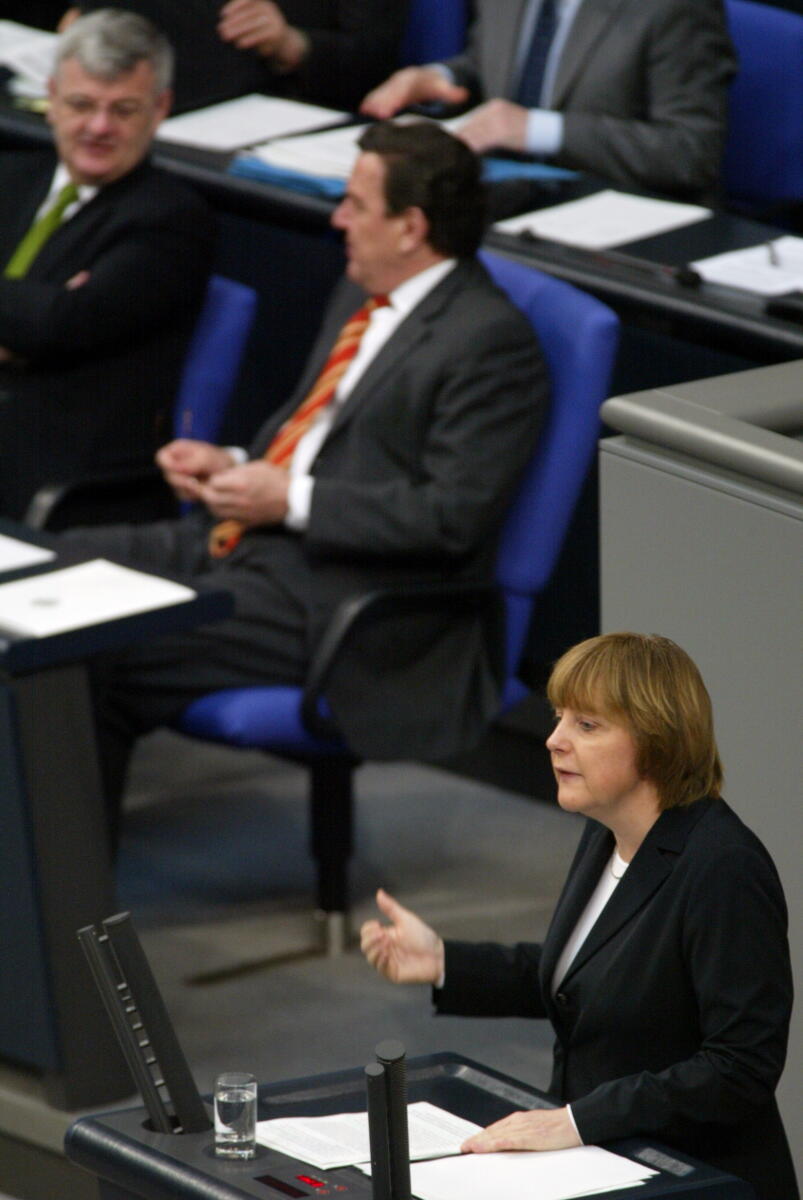 Merkel, Angela; Fischer, Joseph; Schröder, Gerhard Dr. Angela Merkel, CDU, Partei- und Fraktionsvorsitzende, am Rednerpult.; Im Hindergrund: Joseph (Joschka) Fischer, Bündnis 90/Die Grünen, Bundesminister des Auswärtigen und Gerhard Schröder, SPD, Bundeskanzler; Abgeordnete, MdB, CDU/CSU-Fraktion, SPD-Fraktion, Rede, redend, Geste, Gestik