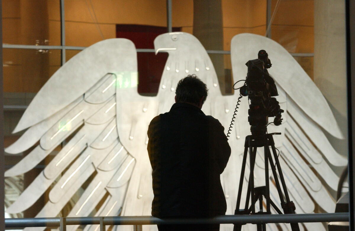  Ein Kameramann auf der Pressetribüne; im Hintergrund der Bundestagsadler.; Medien, Presse, Kamera, Stativ, Adler