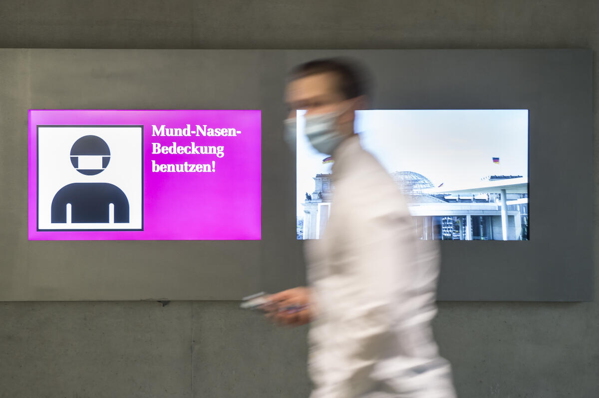 Eine Person mit Maske geht an einer elektronischen Hinweistafel zum Tragen des Mund-Nasen-Schutzes aufgrund der Covid-19-Pandemie im Paul-Löbe-Haus vorbei. Eine Person mit Maske geht an einer elektronischen Hinweistafel zum Tragen des Mund-Nasen-Schutzes aufgrund der Covid-19-Pandemie im Paul-Löbe-Haus vorbei.