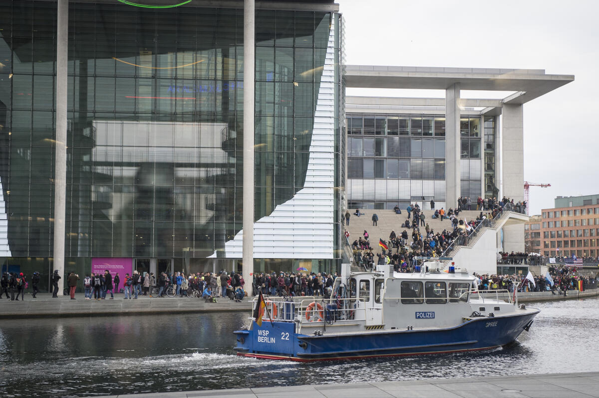 Demonstranten gegen die zur gleichen Zeit im Bundestag beschlossenen Maßnahmen zur Covid-19-Pandemie demonstrieren vor dem Marie-Elisabeth-Lüders-Haus während ein Polizeiboot auf der Spree an ihnen vorbei fährt. Demonstranten gegen die zur gleichen Zeit im Bundestag beschlossenen Maßnahmen zur Covid-19-Pandemie demonstrieren vor dem Marie-Elisabeth-Lüders-Haus während ein Polizeiboot auf der Spree an ihnen vorbei fährt.