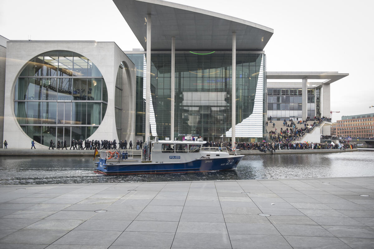 Demonstranten gegen die zur gleichen Zeit im Bundestag beschlossenen Maßnahmen zur Covid-19-Pandemie demonstrieren vor dem Marie-Elisabeth-Lüders-Haus während ein Polizeiboot auf der Spree an ihnen vorbei fährt. Demonstranten gegen die zur gleichen Zeit im Bundestag beschlossenen Maßnahmen zur Covid-19-Pandemie demonstrieren vor dem Marie-Elisabeth-Lüders-Haus während ein Polizeiboot auf der Spree an ihnen vorbei fährt.