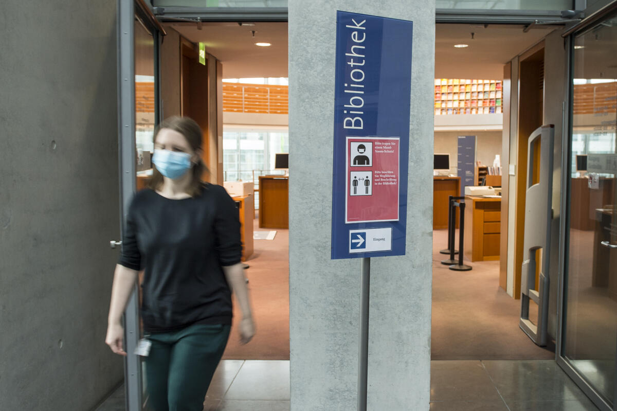 Eine Person geht an einer Hinweistafel zur Abstandsregelung aufgrund der Covid-19-Pandemie an der Bibliothek im Marie-Elisabeth-Lüders-Haus vorbei. Eine Person geht an einer Hinweistafel zur Abstandsregelung aufgrund der Covid-19-Pandemie an der Bibliothek im Marie-Elisabeth-Lüders-Haus vorbei.
