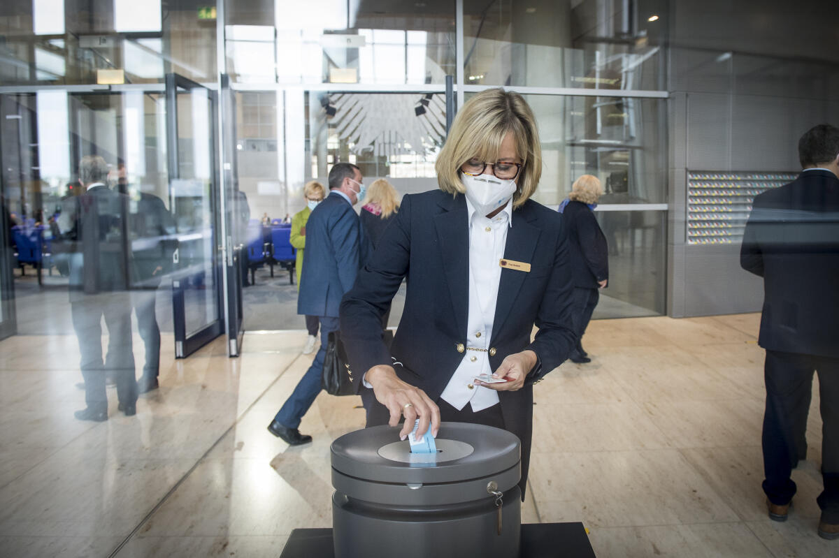 Namentliche Abstimmung über das Abgeordnetengesetz (Wahlgesetz) - Stimmabgabe der Abgeordneten in der Westlobby mit Gesichtsmaske: Saalmeisterin Frau Rubbel wirft stellvertretend Stimmkarten ein. Namentliche Abstimmung über das Abgeordnetengesetz (Wahlgesetz) - Stimmabgabe der Abgeordneten in der Westlobby mit Gesichtsmaske: Saalmeisterin Frau Rubbel wirft stellvertretend Stimmkarten ein.