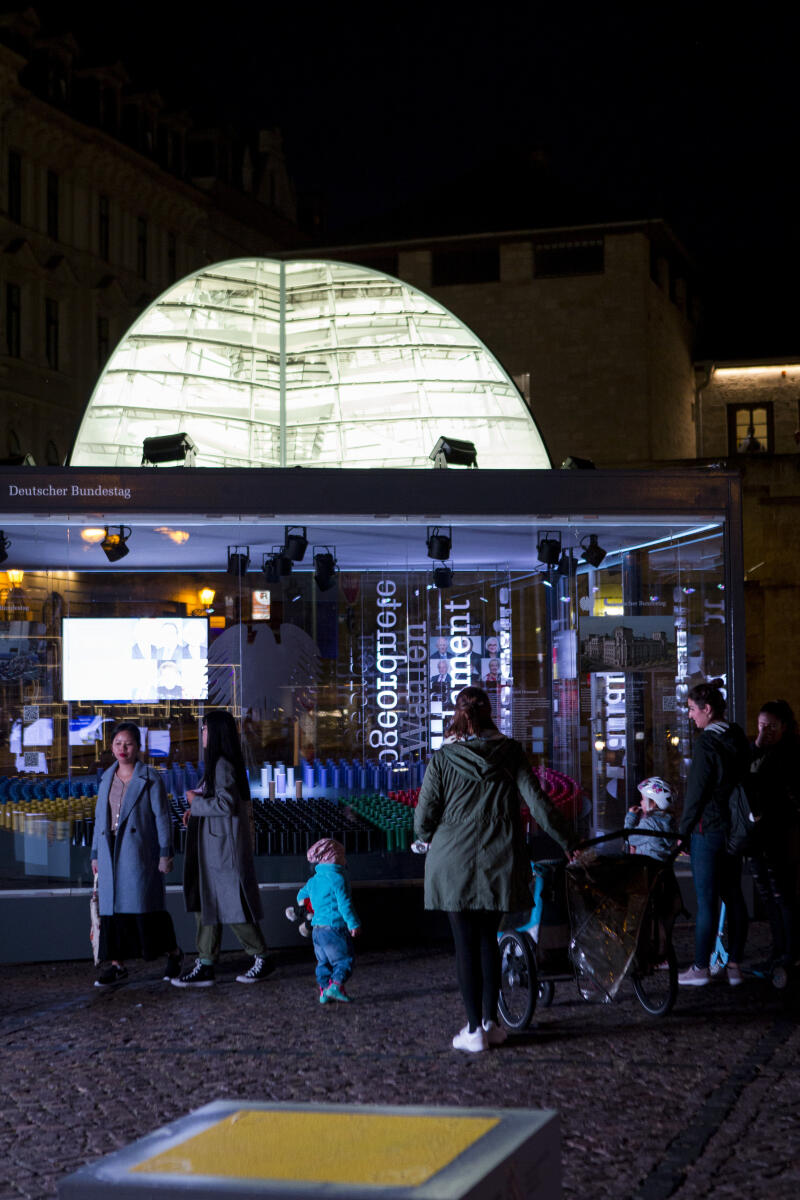 Besucher am Abend vor dem beleuchteten Glaskubus mit Informationen über den Deutschen Bundestag am Eröffnungstag der Einheits-EXPO in Halle (Saale). Zum Tag der deutschen Einheit am 3.Oktober werden die diesjährigen Feierlichkeiten vom 18.09.21 bis zum 03.10.21 in Halle (Saale) abgehalten. Auf dem Hallmarkt sind sämtliche Verfassungsorgane mit Ständen und kleinen Ausstellungen vertreten. Besucher am Abend vor dem beleuchteten Glaskubus mit Informationen über den Deutschen Bundestag am Eröffnungstag der Einheits-EXPO in Halle (Saale). Zum Tag der deutschen Einheit am 3.Oktober werden die diesjährigen Feierlichkeiten vom 18.09.21 bis zum 03.10.21 in Halle (Saale) abgehalten. Auf dem Hallmarkt sind sämtliche Verfassungsorgane mit Ständen und kleinen Ausstellungen vertreten.