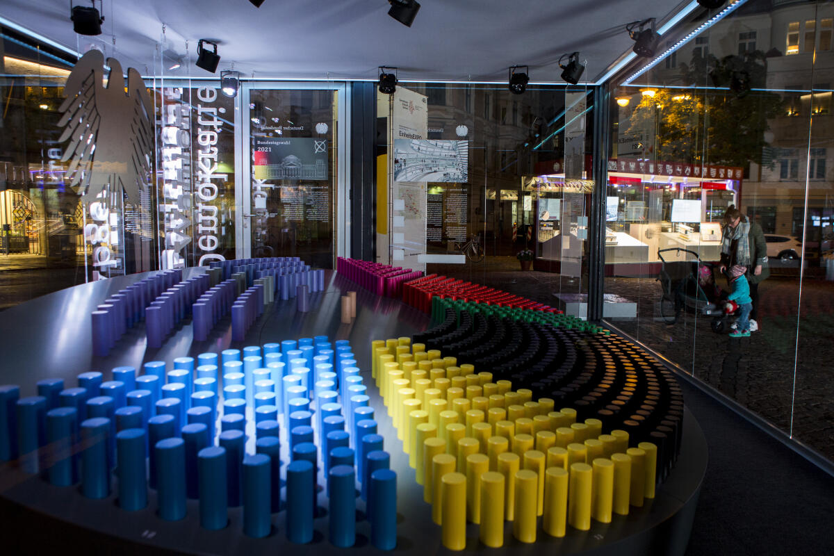  Beleuchtete Sitzverteilung im Glaskubus mit Informationen über den Deutschen Bundestag am Eröffnungstag der Einheits-EXPO in Halle (Saale). Zum Tag der deutschen Einheit am 3.Oktober werden die diesjährigen Feierlichkeiten vom 18.09.21 bis zum 03.10.21 in Halle (Saale) abgehalten. Auf dem Hallmarkt sind sämtliche Verfassungsorgane mit Ständen und kleinen Ausstellungen vertreten.