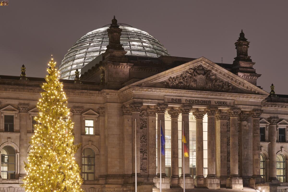 Beleuchteter Weihnachtsbaum auf dem Platz der Republik vor dem Westeingang des Reichstagsgebäudes mit dem Schriftzug "Dem Deutschen Volke". Oben auf dem Gebäude ist die beleuchtete Kuppel zu sehen. Beleuchteter Weihnachtsbaum auf dem Platz der Republik vor dem Westeingang des Reichstagsgebäudes mit dem Schriftzug "Dem Deutschen Volke". Oben auf dem Gebäude ist die beleuchtete Kuppel zu sehen.