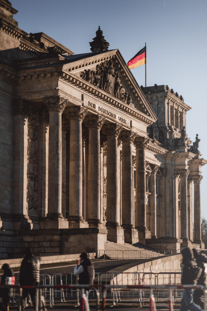  Blick auf das Westportal des Reichstagsgebäudes mit der Inschrift Dem Deutschen Volke. Auf dem Eckturm weht die Fahne der Bundesrepublik Deutschland. 