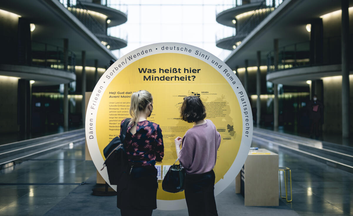  Finissage der Ausstellung "Was heißt hier Minderheit?" in der Halle des Paul-Löbe-Hauses. Unter dem Titel „Was heißt hier Minderheit?“ präsentiert der Deutsche Bundestag eine interaktive Ausstellung, die den Besuchenden das Leben, die Kulturen und die Sprachen der vier nationalen Minderheiten und Volksgruppen Deutschlands – der Dänen, der Friesen, der deutschen Sinti und Roma sowie der Sorben/Wenden – sowie der Sprechergruppe Niederdeutsch näher bringen will.; Hier sehen sich Besucherinnen ein Ausstellungsexponat an.; Die Ausstellung wird vom 17. März bis zum 8. April 2022 im Paul-Löbe-Haus präsentiert.