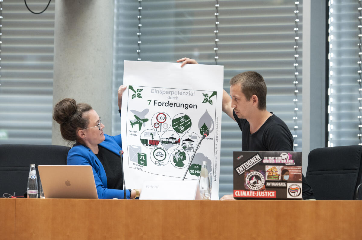 Katja Diehl (L), Expertin für inklusive und nachhaltige Mobilität, und Petent, Tino Pfaff (R), entrollen ein Plakat während der 15. Sitzung des Petitionsausschusses zur Petition Energetische Unabhängigkeit von Russland und Mobilitätswende im Sitzungssaal im Paul-Löbe-Haus. Katja Diehl (L), Expertin für inklusive und nachhaltige Mobilität, und Petent, Tino Pfaff (R), entrollen ein Plakat während der 15. Sitzung des Petitionsausschusses zur Petition Energetische Unabhängigkeit von Russland und Mobilitätswende im Sitzungssaal im Paul-Löbe-Haus.