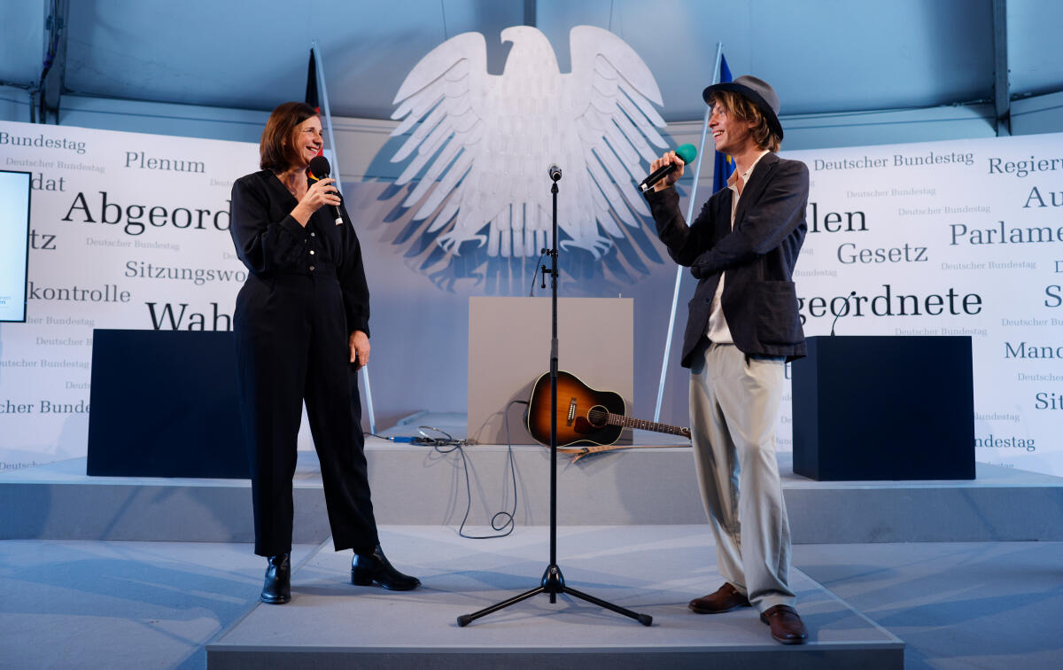 Anlässlich der Feierlichkeiten zum Tag der Deutschen Einheit präsentiert sich der Deutsche Bundestag vom 1. bis 3. Oktober 2022 auf dem Domplatz in Erfurt. Der Deutsche Bundestag bietet seinen Gästen ein abwechslungsreiches und unterhaltsames Programm. Wissenswertes über das Parlament erfahren die Gäste im „Kommunikationsforum“. Es werden verschiedene Informationsmaterialien rund ums Parlament ausgegeben und multimediale Angebote und Spiele für alle Altersgruppen zur Verfügung stehen. ; Hier im Gespräch Bundestagsvizepräsidentin Katrin Göring-Eckardt, Bündnis 90/Die Grünen, MdB, (links), und Max Prosa, Musiker, Lyriker und Theaterautor, (rechts), im Forum Plenarsaal. Göring-Eckardt, Katrin; Prosa, Max Anlässlich der Feierlichkeiten zum Tag der Deutschen Einheit präsentiert sich der Deutsche Bundestag vom 1. bis 3. Oktober 2022 auf dem Domplatz in Erfurt. Der Deutsche Bundestag bietet seinen Gästen ein abwechslungsreiches und unterhaltsames Programm. Wissenswertes über das Parlament erfahren die Gäste im „Kommunikationsforum“. Es werden verschiedene Informationsmaterialien rund ums Parlament ausgegeben und multimediale Angebote und Spiele für alle Altersgruppen zur Verfügung stehen. ; Hier im Gespräch Bundestagsvizepräsidentin Katrin Göring-Eckardt, Bündnis 90/Die Grünen, MdB, (links), und Max Prosa, Musiker, Lyriker und Theaterautor, (rechts), im Forum Plenarsaal.
