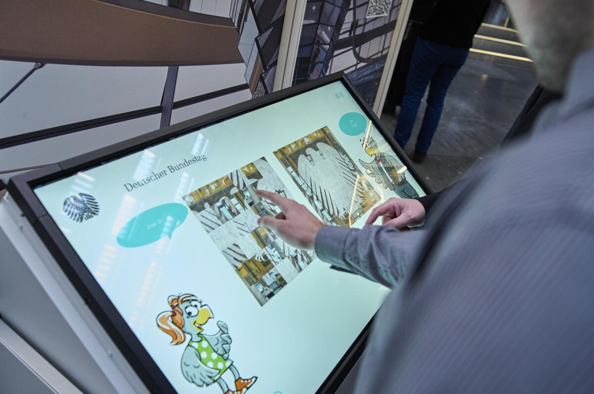  Besucherinnen und Besucher sehen sich die Wanderausstellung des Deutschen Bundestages, hier den Multitouch-Tisch mit interaktiven Angeboten, in der Halle des Paul-Löbe-Hauses an. 