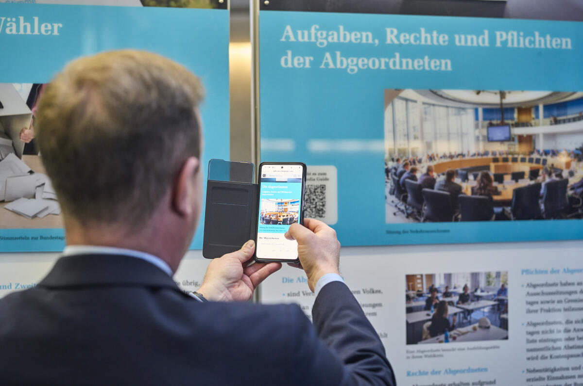  Wanderausstellung des Deutschen Bundestages in der Halle des Paul-Löbe-Hauses. Ein Besucher scannt mit einem Mobiltelefon einen QR-Code, um sich weitere interaktive Inhalte der Ausstellung im begleitenden Multimedia-Guide anzusehen. 