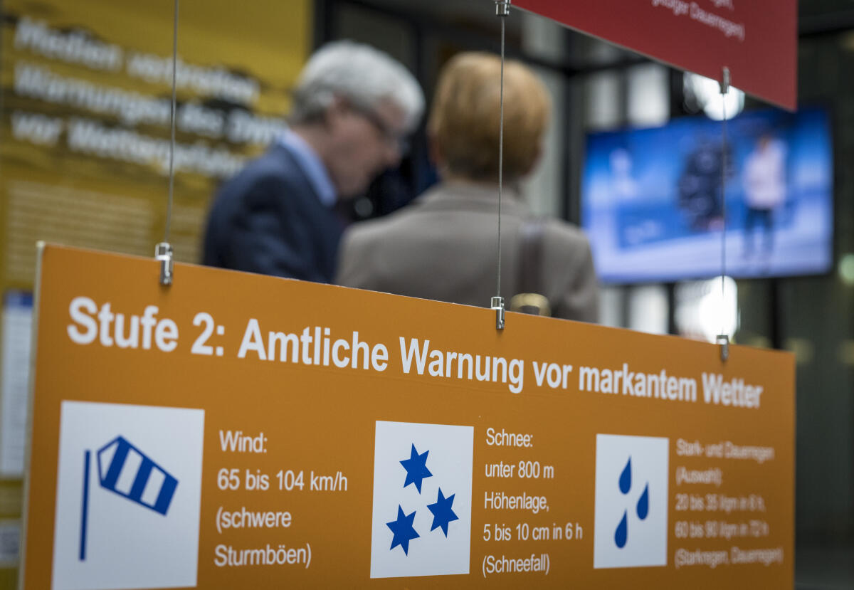  Besucherinnen und Besucher beim Rundgang nach der Eröffnung der Ausstellung "70 Jahre zwischen Natur und Gesellschaft" anlässlich des 70. Jubiläums des Deutschen Wetterdienstes. Hier ein Exponat mit Symbolen für amtliche Warnungen vor markantem Wetter. 