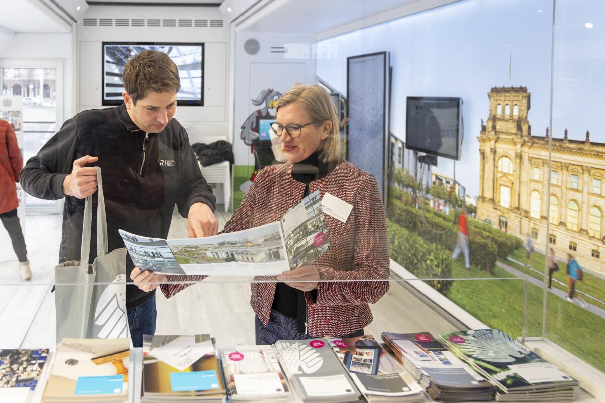 Infomobil des Deutschen Bundestages in Rostock, "Neuer Markt". Besucherinnen und Besucher informieren sich am Infotresen mit Broschüren und Flyern über die Arbeit des Deutschen Bundestages. Infomobil des Deutschen Bundestages in Rostock, "Neuer Markt". Besucherinnen und Besucher informieren sich am Infotresen mit Broschüren und Flyern über die Arbeit des Deutschen Bundestages.
