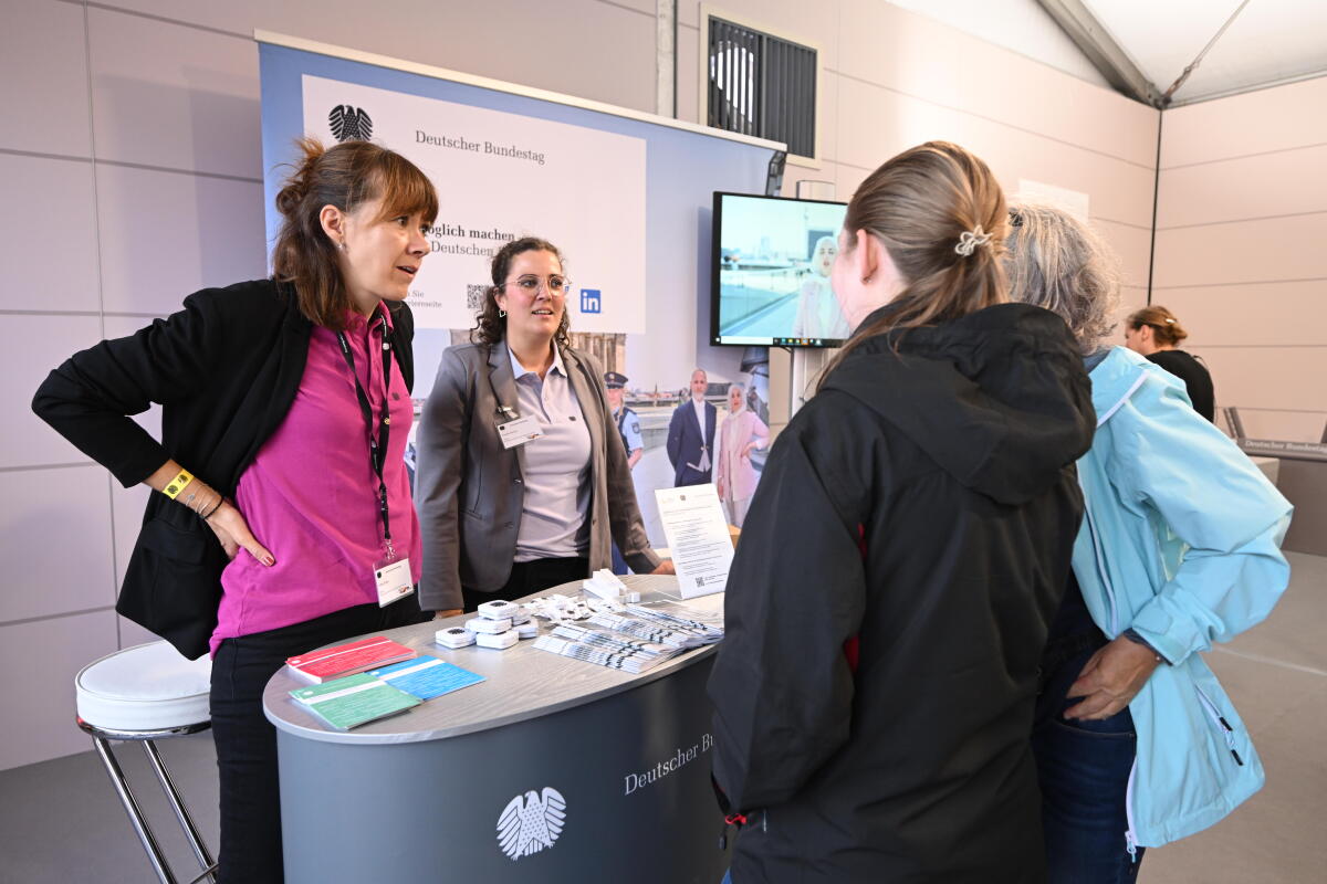  Mitarbeiterinnen und Mitarbeiter im Gespräch mit Besucherinnen und Besuchern am Stand der Referates ZV1, ZV2 Personal im Kommunikationsforum und Zelt des Deutschen Bundestages auf der Festveranstaltung zum Tag der Deutschen Einheit in Hamburg.