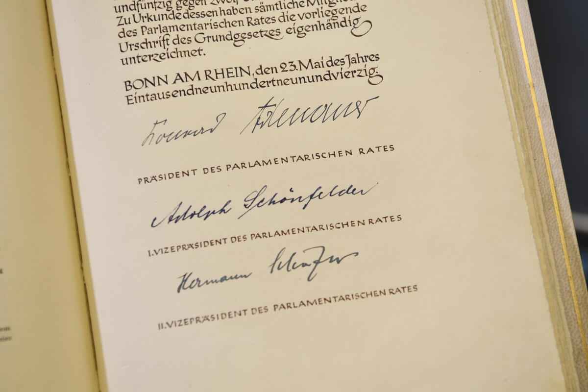 Blick auf die Urschrift des Grundgesetzes der Bundesrepublik Deutschland. Hier ist die Seite mit den Unterschriften des Präsidenten des Parlamentarischen Rates Konrad Adenauer, sowie des Ersten Vizepräsidenten des Parlamentarischen Rates Adolph Schönfelder und des Zweiten Vizepräsidenten des Parlamentarischen Rates Hermann Schäfer zu sehen.; Blick auf die Urschrift des Grundgesetzes der Bundesrepublik Deutschland. Hier ist die Seite mit den Unterschriften des Präsidenten des Parlamentarischen Rates Konrad Adenauer, sowie des Ersten Vizepräsidenten des Parlamentarischen Rates Adolph Schönfelder und des Zweiten Vizepräsidenten des Parlamentarischen Rates Hermann Schäfer zu sehen.;