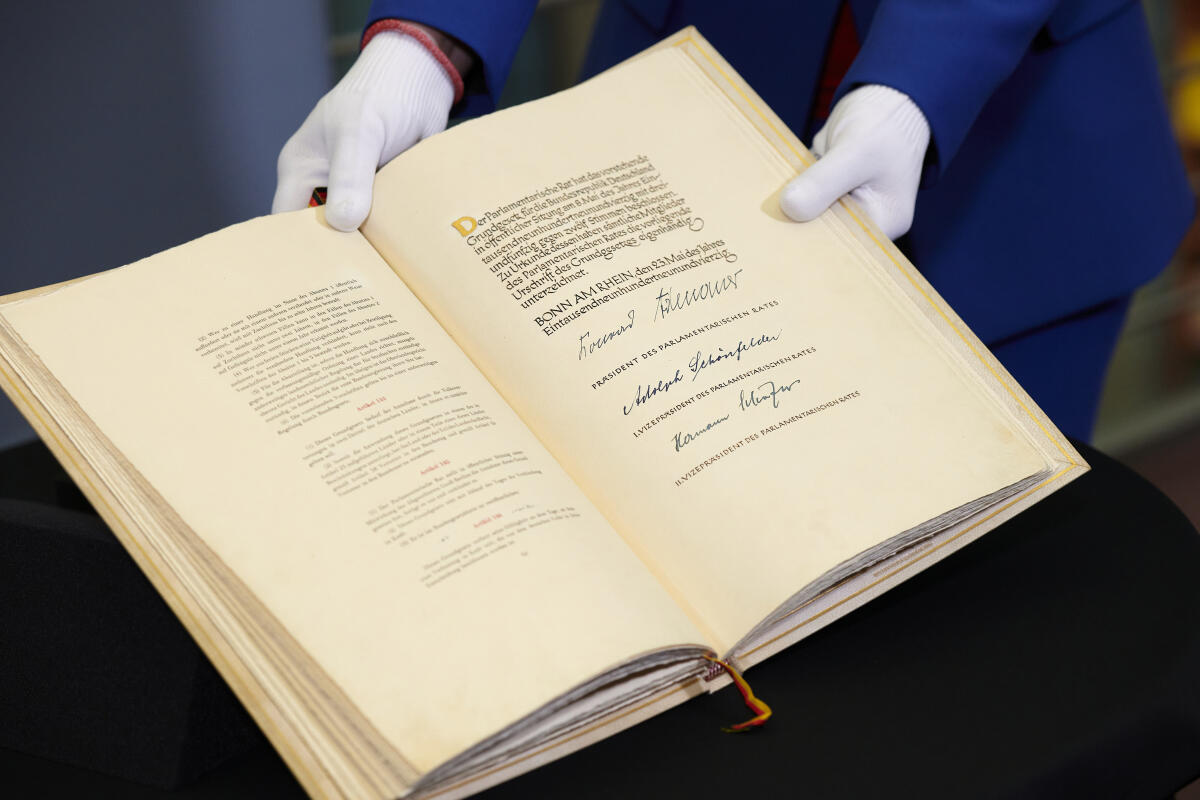 Blick auf die Urschrift des Grundgesetzes der Bundesrepublik Deutschland. Hier ist die Seite mit den Unterschriften des Präsidenten des Parlamentarischen Rates Konrad Adenauer, des Ersten Vizepräsidenten des Parlamentarischen Rates Adolph Schönfelder und des Zweiten Vizepräsidenten des Parlamentarischen Rates Hermann Schäfer, sowie die Artikel 144 bis 146 zu sehen.; Blick auf die Urschrift des Grundgesetzes der Bundesrepublik Deutschland. Hier ist die Seite mit den Unterschriften des Präsidenten des Parlamentarischen Rates Konrad Adenauer, des Ersten Vizepräsidenten des Parlamentarischen Rates Adolph Schönfelder und des Zweiten Vizepräsidenten des Parlamentarischen Rates Hermann Schäfer, sowie die Artikel 144 bis 146 zu sehen.;