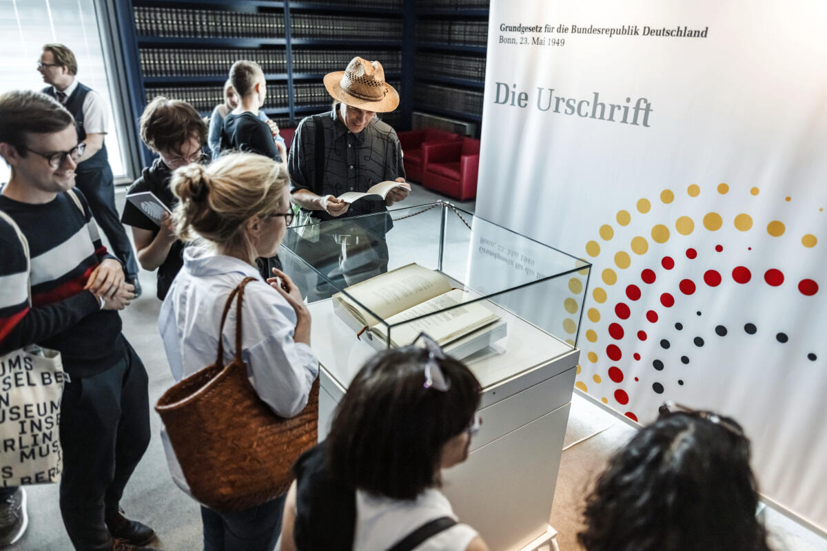  Vor 75 Jahren, am 23. Mai 1949, wurde das Grundgesetz für die Bundesrepublik Deutschland verkündet. Der Deutsche Bundestag beteiligt sich am Demokratiefest der Bundesregierung und öffnet vom 24. bis 26. Mai das Reichstagsgebäude und das Paul-Löbe-Haus für Interessierte. Aus diesem Anlass findet eine Ausstellung der Urschrift des Grundgesetzes in der Präsenzbibliothek im Reichstagsgebäude statt. Besucherinnen und Besucher betrachten die Urschrift des Grundgesetzes, welches in einer Vitrine ausgestellt ist.