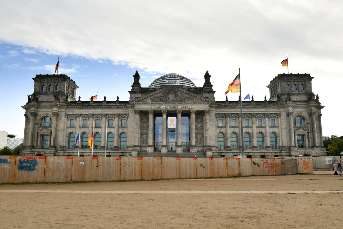  Gemeinsame Solidaritätsbekundung aller Verfassungsorgane durch Hängung eines gelben Schleifenbanners (Awareness Ribbon) mit der Aufschrift "07. Oktober 2023" zum Jahrestag des Angriffs der Hamas auf Israel am 7. Oktober 2024. Hier am Westportal des Reichstagsgebäudes mit Trauerbeflaggung der Europa- und Deutschlandflaggen auf Halbmast.