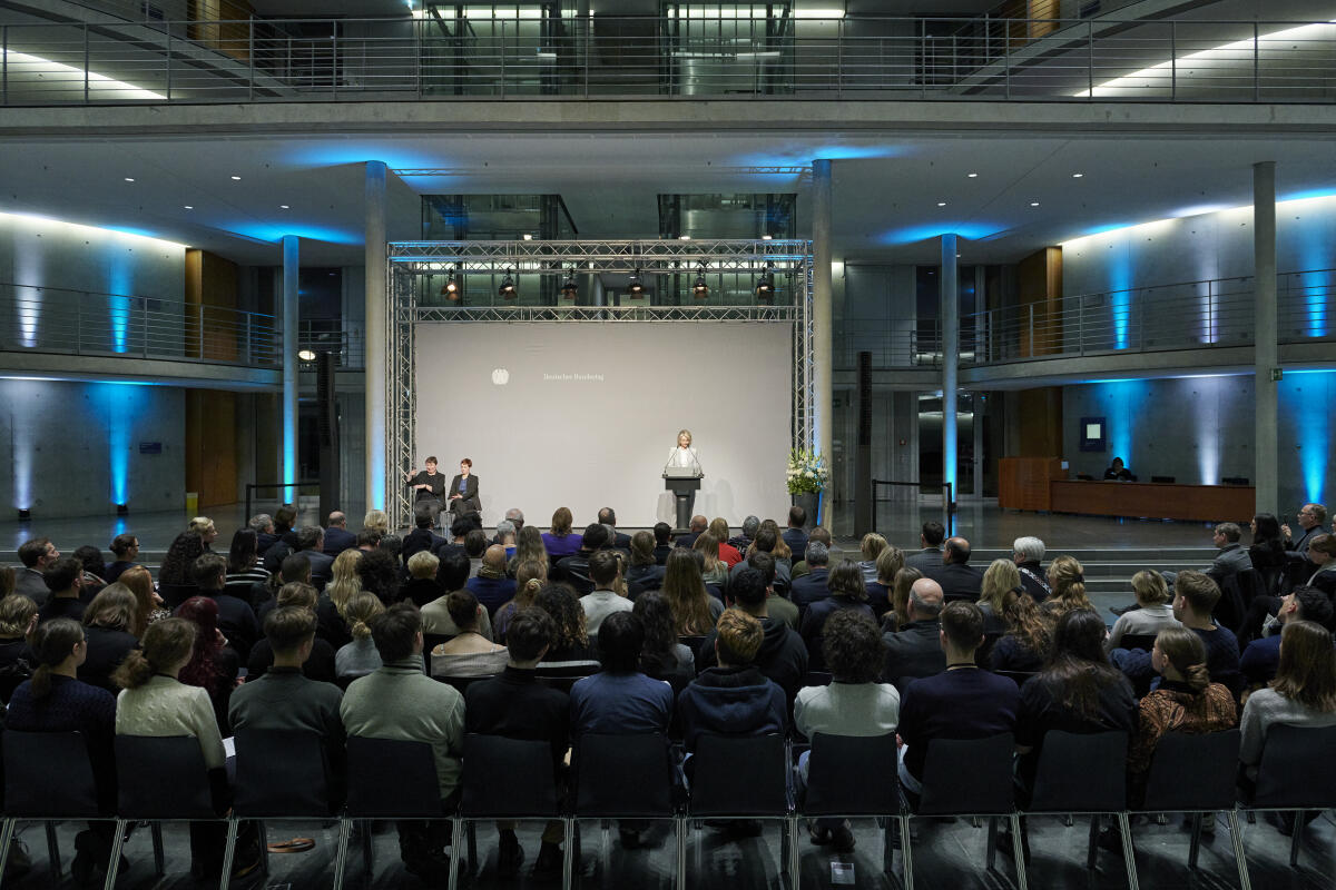  Monika Mendat, Künstlerin, spricht zur Eröffnung ihrer Ausstellung "Erinnerung an die Befreiung - Mahnung für die Demokratie" im Paul-Löbe-Haus aus Anlass des 80. Jahrestags der Befreiung von Auschwitz. Blick auf die Bühne.