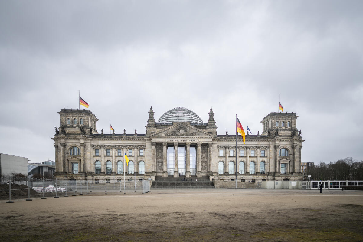  Flaggen des Reichstagsgebäudes auf Halbmast. Anlässlich des russischen Angriffskrieges auf die Ukraine ist die Flagge der Ukraine vor dem Westportal gehisst.