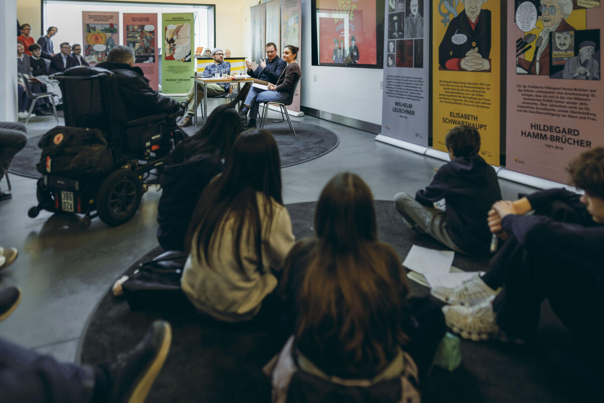  Mit dem „Tag der Demokratiegeschichte 2026“ soll unter der Schirmherrschaft von Bundespräsident Frank-Walter Steinmeier  erstmals mit einem bundesweiten Aktionstag die Geschichte der Demokratie gewürdigt werden. Der Deutsche Bundestag beteiligt sich im Aktionszeitraum mit mehreren Veranstaltungen. ; Graphic Novelist Simon Schwartz, Autor Jan Ruhkopf und Moderatorin Verena Mink im Rahmen der Buchpräsentation „100 Köpfe der Demokratie - Starke Stimmen für ein Leben in Freiheit“ – ein bildreiches Sachbuch zur deutschen Demokratiegeschichte. Eine Kooperation mit der Stiftung Bundespräsident-Theodor-Heuss-Haus. Übersicht während des Gespräches.