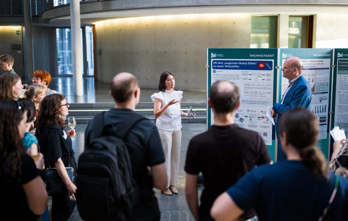 „Schumann; Kiara“ Eröffnung der Ausstellung "Poster im Bundestag: Wissenschaftsfreiheit - die Freiheit zu forschen" in der Halle des Paul-Löbe-Hauses: Kiara Schumann (l), beteiligte Studierende der Universität Konstanz, im Gespräch vor ihrem Poster in der Ausstellung.; 